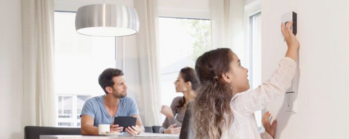 Ein Mann und eine Frau sitzten an einem Tisch, das Kind bedient einen Digitalregler